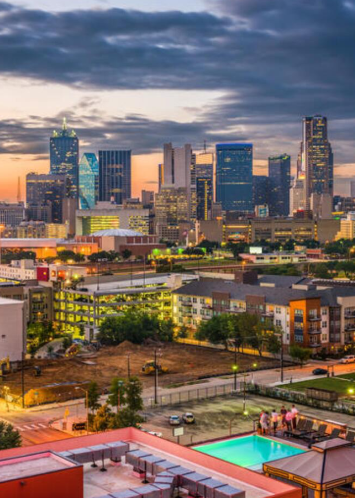 A breathtaking sunset view over Arlington, Texas, with the sky glowing in warm hues of orange, pink, and purple. The city's skyline features a mix of modern buildings and iconic landmarks bathed in the fading sunlight. AT&T Stadium and Globe Life Field stand prominently, their silhouettes contrasting against the vibrant sky. Below, the city lights begin to twinkle, illuminating the streets and entertainment districts. In the distance, the vast Texas landscape stretches beyond the urban center, capturing the dynamic energy and charm of Arlington as day transitions into night.