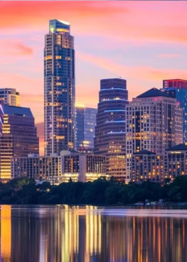 A breathtaking sunset view over Austin, Texas, with the sky glowing in warm hues of orange, pink, and purple. The city skyline, featuring the Texas State Capitol and modern high-rises, is bathed in the fading sunlight. Below, the shimmering waters of Lady Bird Lake reflect the vibrant colors, while the bridges spanning the river add depth to the scene. As the city lights begin to twinkle, the lively atmosphere of Austin’s music and culture comes to life. In the distance, the rolling Texas Hill Country creates a stunning backdrop, capturing the perfect blend of urban energy and natural beauty as day transitions into night.